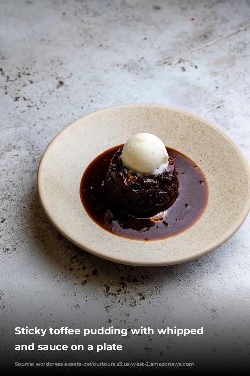 Sticky toffee pudding with whipped cream and sauce on a plate