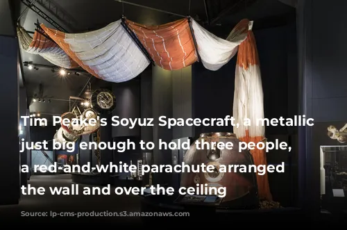 Tim Peake's Soyuz Spacecraft, a metallic capsule just big enough to hold three people, with a red-and-white parachute arranged up the wall and over the ceiling