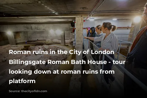 Roman ruins in the City of London - Billingsgate Roman Bath House - tour group looking down at roman ruins from viewing platform