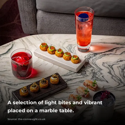 A selection of light bites and vibrant cocktails placed on a marble table.