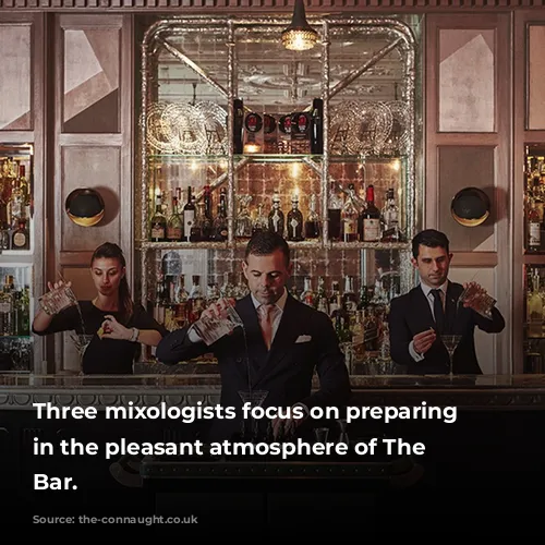 Three mixologists focus on preparing cocktails in the pleasant atmosphere of The Connaught Bar.