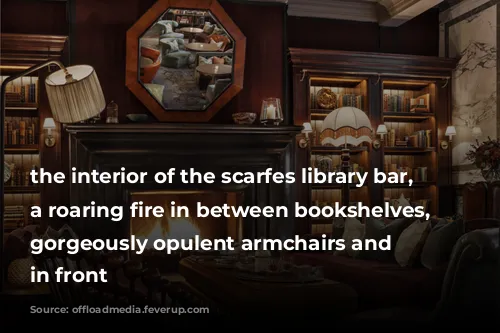 the interior of the scarfes library bar, showing a roaring fire in between bookshelves, with gorgeously opulent armchairs and sofas in front