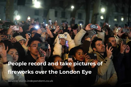 People record and take pictures of the fireworks over the London Eye