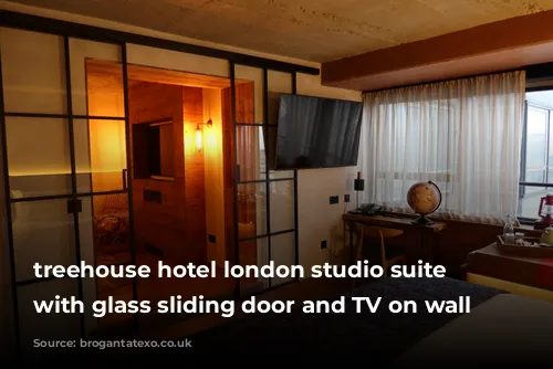 treehouse hotel london studio suite bedroom with glass sliding door and TV on wall