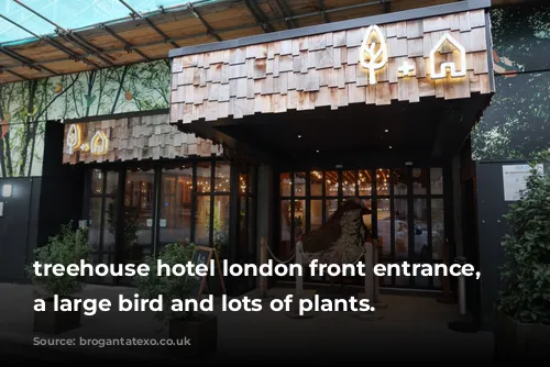 treehouse hotel london front entrance, featuring a large bird and lots of plants.