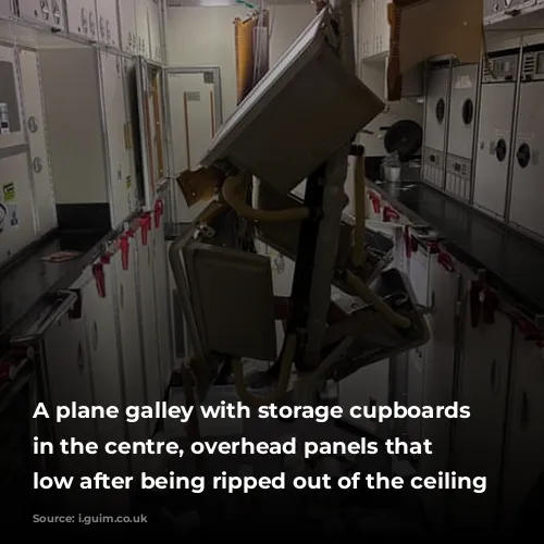  A plane galley with storage cupboards and, in the centre, overhead panels that hang low after being ripped out of the ceiling