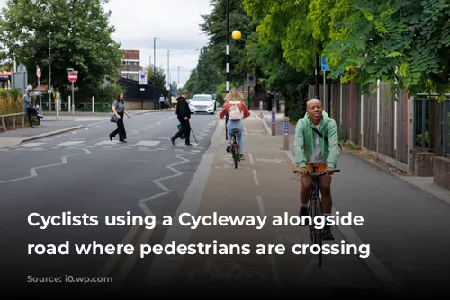 Cyclists using a Cycleway alongside a road where pedestrians are crossing