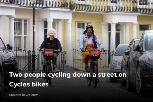 Two people cycling down a street on Santander Cycles bikes