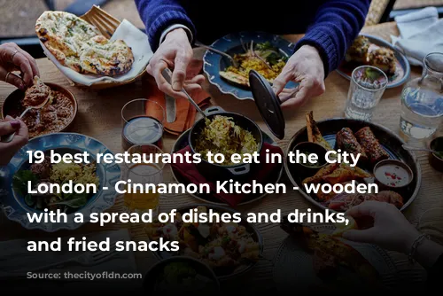 19 best restaurants to eat in the City of London - Cinnamon Kitchen - wooden table with a spread of dishes and drinks, curry and fried snacks