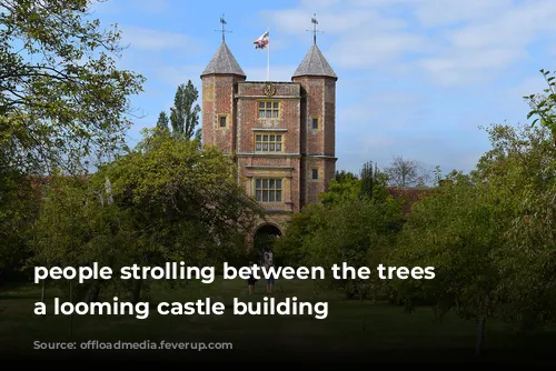 people strolling between the trees towards a looming castle building