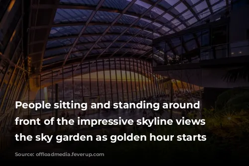 People sitting and standing around in front of the impressive skyline views from the sky garden as golden hour starts