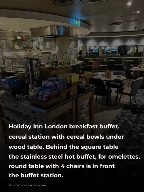 Holiday Inn London breakfast buffet. Cold cereal station with cereal bowls under the wood table. Behind the square table is the stainless steel hot buffet, for omelettes. A round table with 4 chairs is in front on the buffet station. 