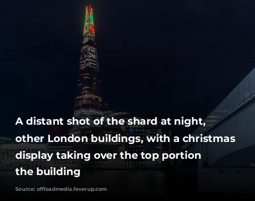 A distant shot of the shard at night, amongst other London buildings, with a christmas light display taking over the top portion of the building