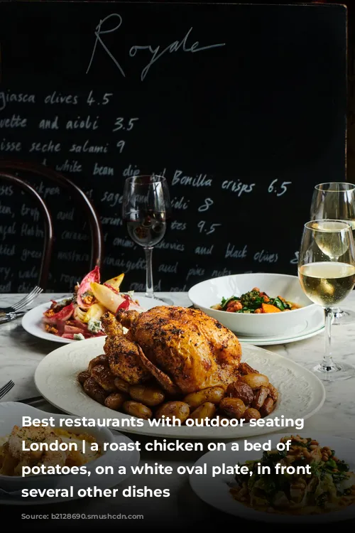 Best restaurants with outdoor seating in London | a roast chicken on a bed of new potatoes, on a white oval plate, in front of several other dishes