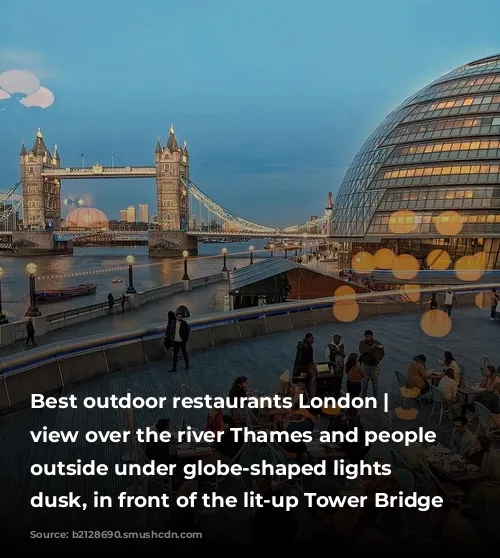 Best outdoor restaurants London | A view over the river Thames and people dining outside under globe-shaped lights at dusk, in front of the lit-up Tower Bridge