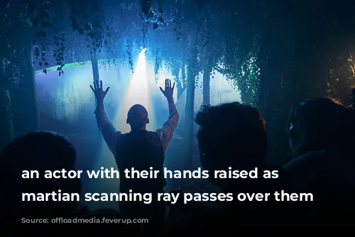 an actor with their hands raised as a martian scanning ray passes over them