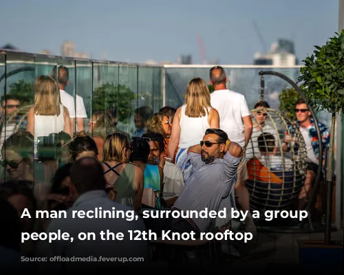 A man reclining, surrounded by a group of people, on the 12th Knot rooftop