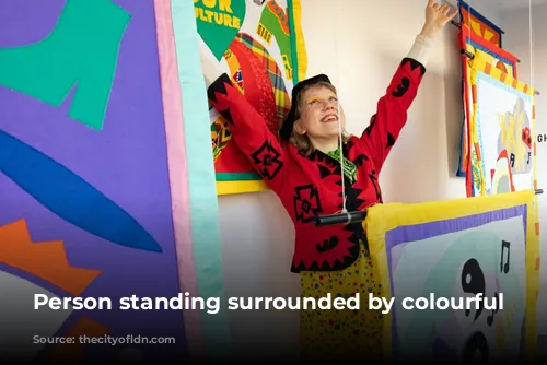 Person standing surrounded by colourful art.