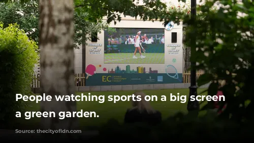 People watching sports on a big screen in a green garden.