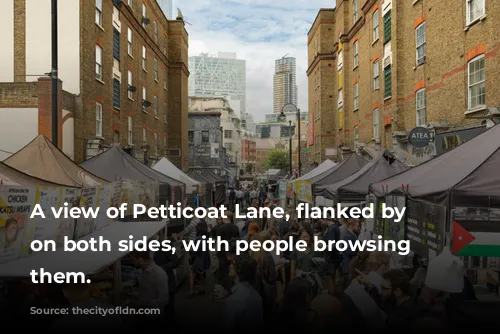 A view of Petticoat Lane, flanked by stalls on both sides, with people browsing through them.