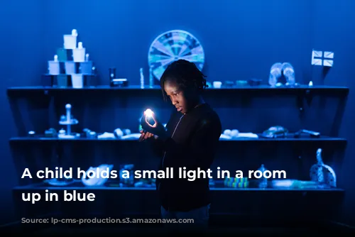 A child holds a small light in a room lit up in blue 