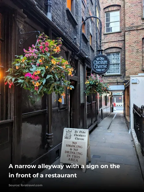 A narrow alleyway with a sign on the ground in front of a restaurant