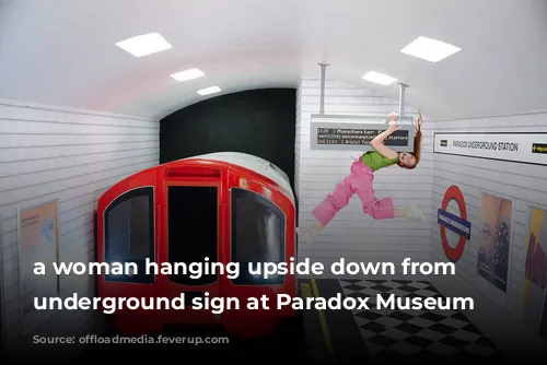 a woman hanging upside down from a underground sign at Paradox Museum